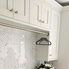 a kitchen with white cabinets and marble backsplash, an oven hood over the stove