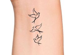 a woman's arm with two birds on it and one bird flying in the air