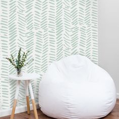 a white bean bag chair sitting next to a small table with a plant on it