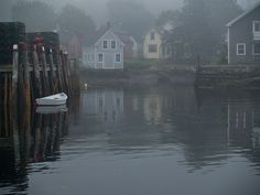 a white boat floating on top of a body of water next to wooden posts and houses