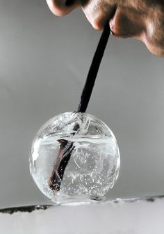 a person is holding a black stick in a glass ball with water and bubbles on it