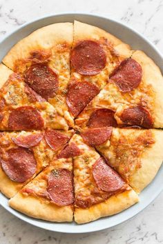 a pepperoni pizza cut into eight slices in a pan on a marble counter top