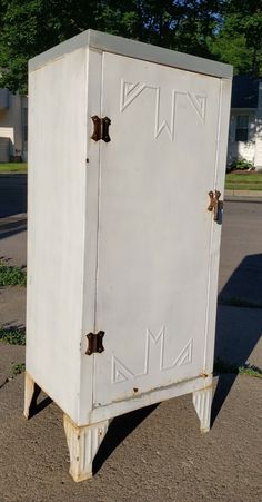 an old white cabinet sitting on the side of a road