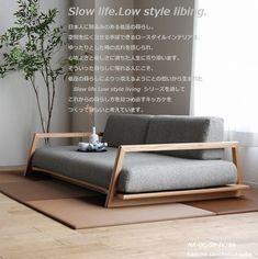 a couch sitting on top of a wooden floor next to a plant in a vase