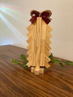 an origami christmas tree made out of wood with a red bow on top