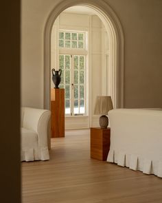 an arched doorway leads to a bedroom with a bed and two chairs