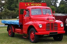 an old red truck is parked in the grass