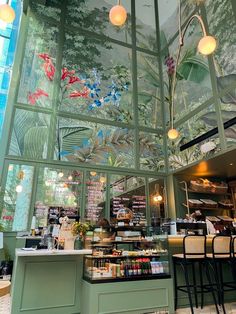 the inside of a restaurant with green walls and glass windows, decorated with floral designs