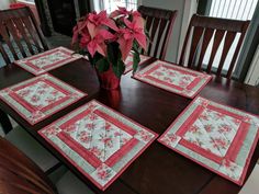 the table is set with four placemats and a vase full of poinsettia