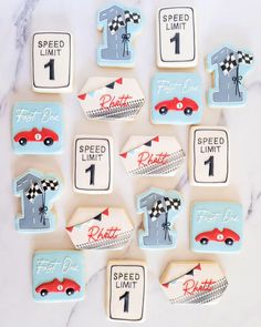 decorated cookies with race cars and numbers are arranged on a marble countertop for a birthday party