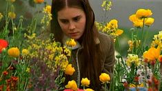 a woman sitting in a field of flowers