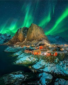 the northern lights shine brightly over houses and mountains in this aerial photo taken on an island