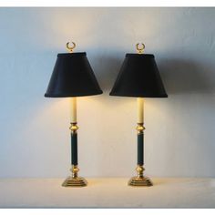 two lamps with black shades and gold trims on each lamp are sitting side by side