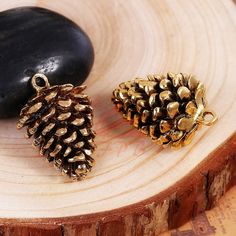 two gold pine cones sitting on top of a wooden table next to a black rock