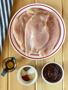 raw chicken on a plate with condiments and seasoning next to the bowl