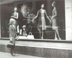 three mannequins are standing in front of a store window, one is holding a purse