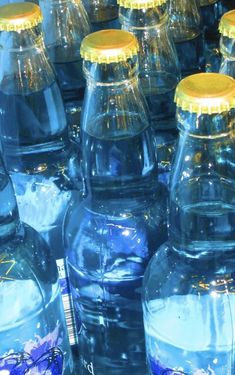 many blue water bottles with yellow lids are lined up