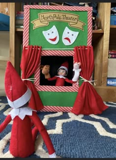 two elfs are sitting in front of a theatre with red curtains and masks on them