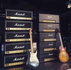 guitars and amps are lined up on the floor in front of an array of other musical equipment