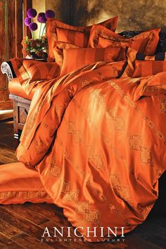 an orange comforter and pillows on a bed