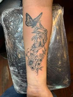 a woman's arm with a tattoo on it that has flowers and a butterfly