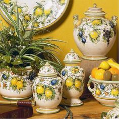 a table topped with yellow and white vases filled with fruit next to a mirror