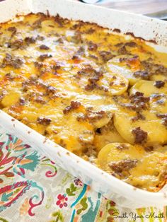 a casserole dish with potatoes and meat in it on a colorful table cloth