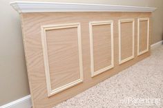 an unfinished paneled wall in a room with carpet and white trim on the walls