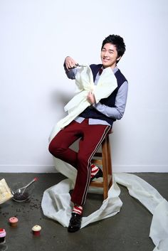 a man sitting on top of a wooden chair holding a white scarf over his shoulder