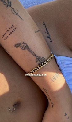 a woman's arm with tattoos on it and a gold chain around her waist