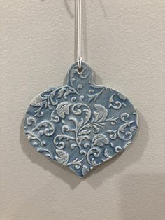 a ceramic ornament hanging from a hook on a wall with a white background