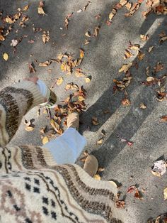 two people standing on the sidewalk with their feet in the air and leaves all around them