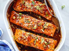 baked salmon with sesame seeds and seasoning in a white casserole dish on top of a blue towel