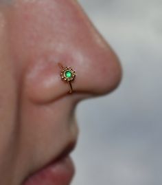 a close up of a person's nose with a green stone in the middle