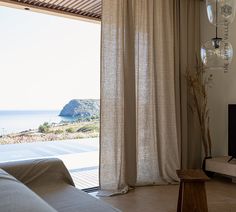 a living room with an open window and view of the ocean from it's patio