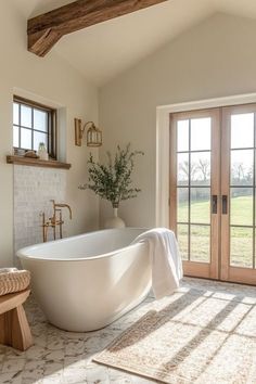 a large white bath tub sitting inside of a bathroom next to a wooden door and window