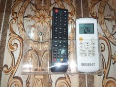 two remote controls sitting on top of a plastic case in front of a floral wallpaper