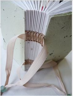 an open book with ribbon on it sitting on a table next to a white surface