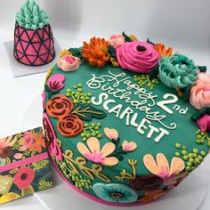 there is a birthday cake with flowers on it and a greeting card next to it