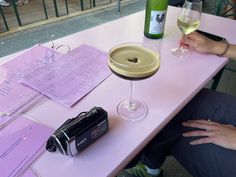 a person sitting at a table with two glasses of wine and papers on the table