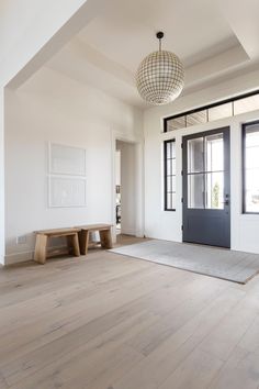 an empty room with wooden flooring and a bench in front of the door that is open