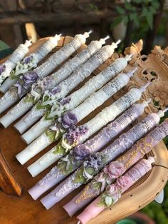 many candles are lined up on a wooden stand with flowers and laces around them