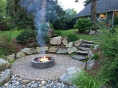 an outdoor fire pit surrounded by rocks and grass