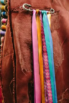 several different colored ribbons are hanging from the back of a brown jacket with metal clasps