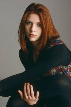 a woman with red hair and blue eyes is posing for a photo in black tights