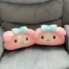 two pink pillows sitting on top of a gray chair