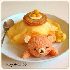 a teddy bear is sitting in front of some food on a plate with a spoon