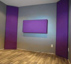 an empty room with purple and grey walls, wood flooring and a painting on the wall