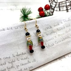 Get ready to sparkle this holiday season with these Nutcracker-inspired earrings!  These charming earrings are a smaller version of my classic crystal Nutcracker dangle earrings, but just as elegant and dazzling. The high-quality Czech crystal glass beads, glass pearls, and crystal rondelle gold-plated spacer beads make for a stunning combination that is sure to turn heads. The Nutcracker design features a black faceted glass rondelle bead for the boots, frosted red matte 3mm glass cube beads fo Nutcracker Jewelry, Beaded Nutcracker Earrings, Christmas Jewelry: Dangling Bead Drop Earrings, Small Dangle Earrings, Nutcracker Soldier, Making Glass, Glass Cube, Surgical Steel Earrings, Czech Crystal