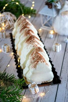 a long piece of cake sitting on top of a black plate next to christmas decorations